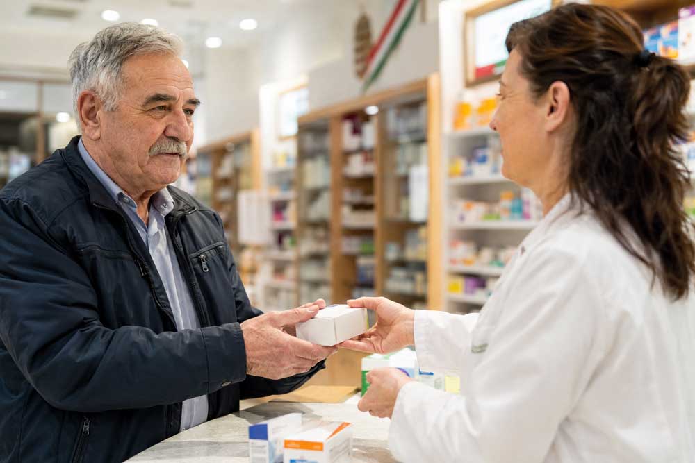 Älterer Mann erhält in einer ungarischen Apotheke Medikamente von einer Apothekerin