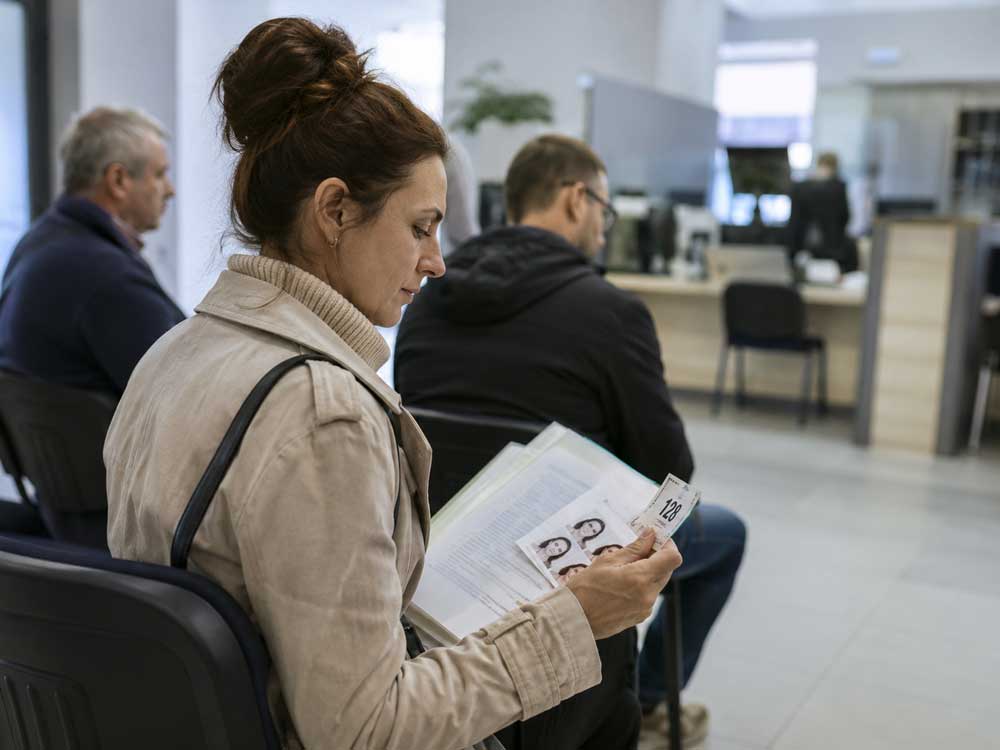 Frau wartet mit Unterlagen und Nummer im ungarischen Amtsbereich als Bild zu Erfahrungsberichte über OIF Termine und Bürokratie in Ungarn